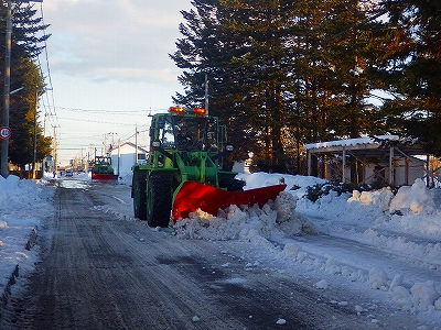 道路の除雪作業をしているショベルカーの写真