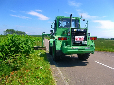 道路脇の雑草を刈っているショベルカーの写真
