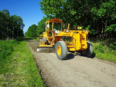 道路の路面整正をしているグレーダーの写真
