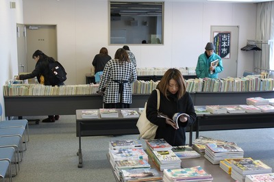 視聴覚室に積まれた廃棄される前の雑誌や書籍の中から、欲しいものがないか熱心に探す様子の町民の方たちの写真
