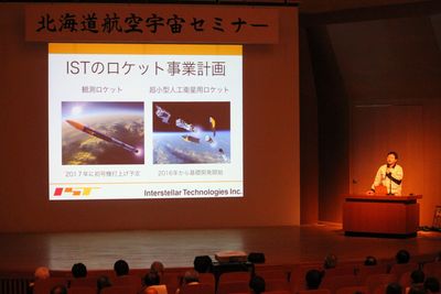 北海道航空宇宙セミナーにて、ステージ壇上からロケット事業計画について講演を行う稲川貴大氏の写真
