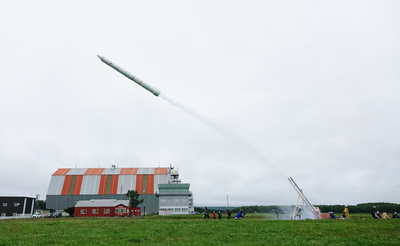 勢いよく水と圧縮空気を噴射して、発射台から大空へ大きく飛翔する巨大ペットボトルロケットの写真