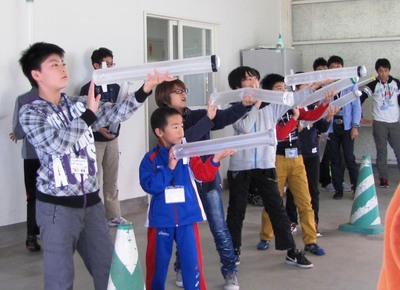 横一列に並んで各々傘袋ロケットの発射姿勢をとる交流会参加者たちの写真