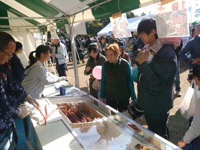 銀河連邦物産展ブースで名産品を見ている人たちの写真