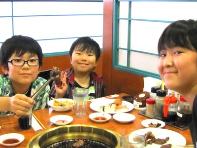 焼肉の席にて、各々笑顔で撮影に応じる児童3名の写真