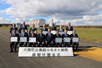 秋の滑走路上にて記念撮影に応じる、酒森町長と式典参加企業代表者たちの集合写真。各企業代表者の手元にはそれぞれ贈呈された感謝状が確認できる