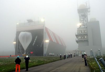 濃霧の中、格納庫から引き出される気球の写真