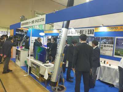 ビジネスEXPOにて、北海道宇宙科学技術創成センター及びSPACE COTANとの共同ブースで来訪者が説明を受けている様子の写真