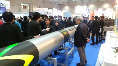 札幌市で開催されたビジネスEXPOで、実物大の観測ロケットを見ている来場者の方たちの写真