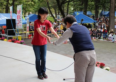 柏林公園の屋外ステージ上で「2013スペースイラストコンテスト」表彰を受ける女子生徒の写真