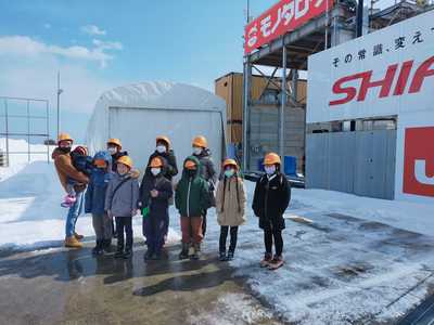 雪の残るロケット発射台付近にて、記念撮影に応じる団員たちの集合写真