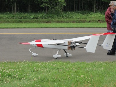 滑走路に置かれた白と赤のカラーリングの小型無人機の写真
