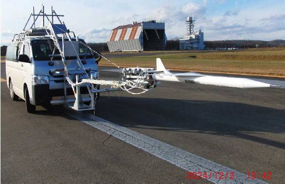 実験用ワゴン車の固定用器具先端に設置された、「オオワシ」の縮小機体の写真