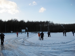 雪の積もった多目的航空公園駐車場にて、製作した凧を飛ばす児童たちの写真
