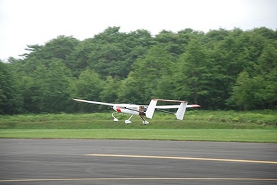 小規模飛行実験で、小型の無人飛行機が低空で滑走路の上を飛んでいる写真