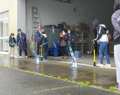 雨天で濡れた路面に発射台を各々展開して、ペットボトルロケットの打ち上げに臨む団員たちの写真