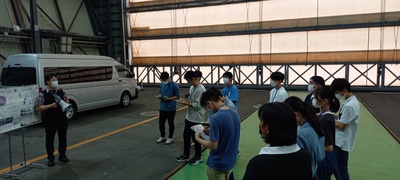 JAXA格納庫内にて講義を受ける参加者たちの写真