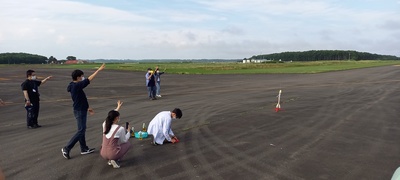 滑走路上にてモデルロケットの打上げ実験に臨む参加者たちの写真