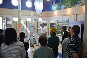 SORAの展示室1にて、職員より展示物の解説を聞く南十勝社会福祉協議会役職員の視察団の写真