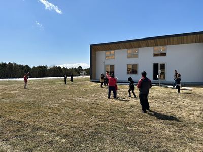 青空の広がる屋外でペーパークラフトを飛ばしている団員たちの写真