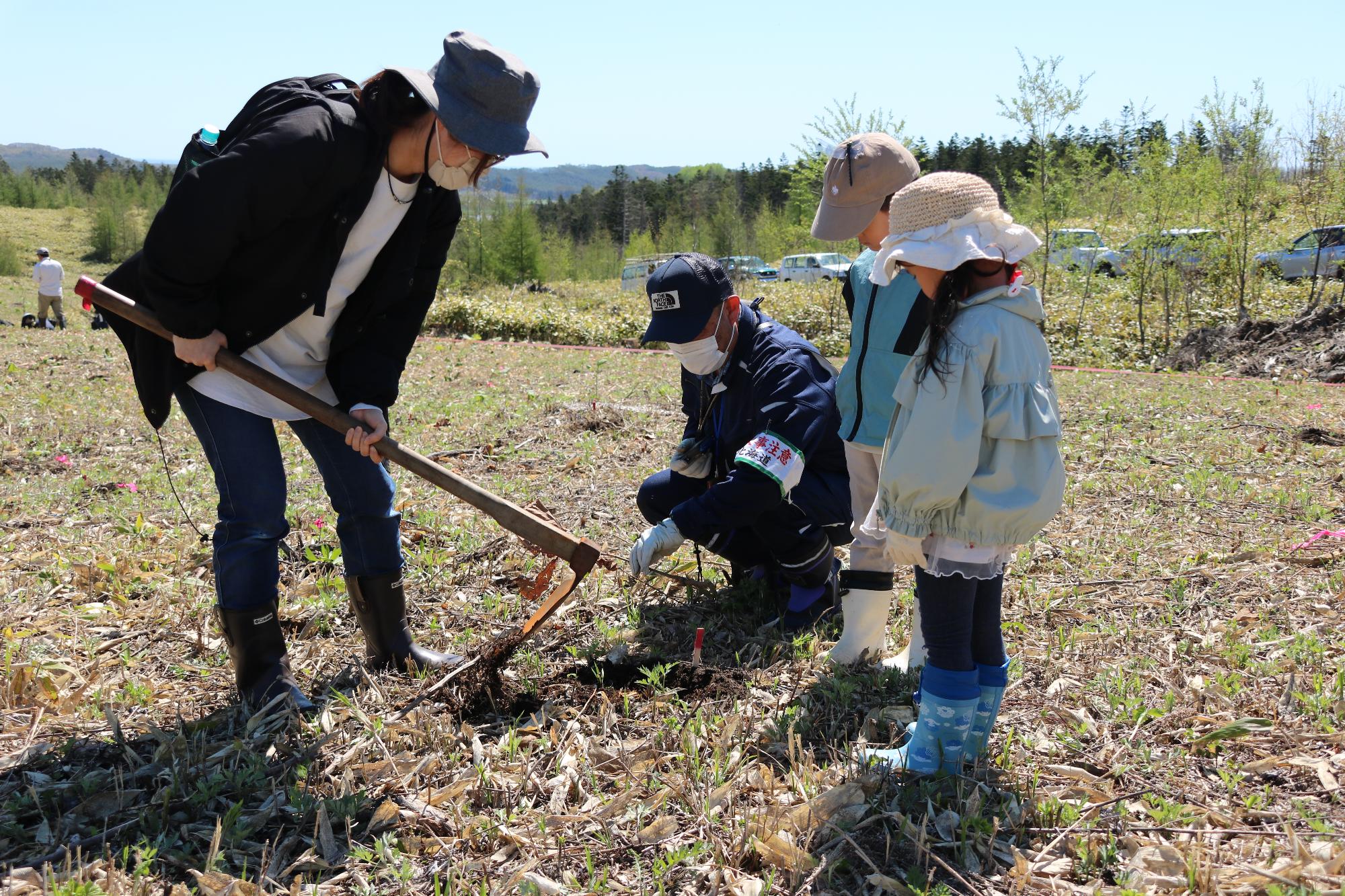 大人と一緒に植樹を行う子どもの写真