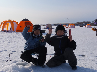 釣具を持ってポーズをとるワカサギ釣りを楽しむ2人の子どもの写真
