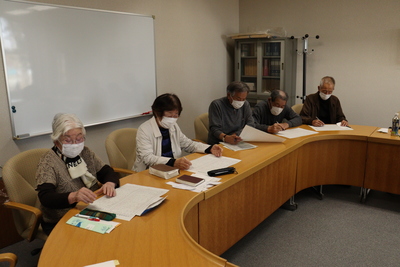 会議室で文芸活動を行っている60歳以上の高齢者の方々の写真
