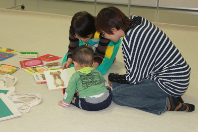 ブックスタートを利用して赤ちゃんに絵本を読み聞かせるスタッフとお母さんの写真