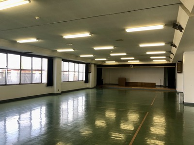 左側に窓があり、光沢のある緑の床のある中会議室の写真