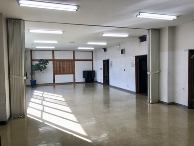部屋の奥にはテレビが置いておあり中央に部屋を横断するカーテンがある小会議室の写真