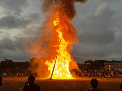 河川敷の会場で大きく燃え上がる、ペルプネ火祭りの巨大な柱松明の写真