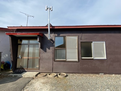 物件No.23の玄関付近の写真。玄関の横にはパイプでできた煙突がある。