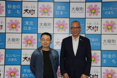 大樹町のバックボードの前に並んでいる佐藤大樹さんと町長の写真