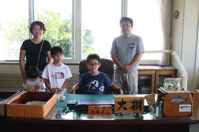 町長の席に座っている中島大樹さんとご家族の写真