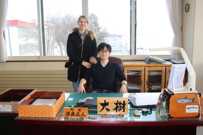町長の席に座っている隅元大樹さんと肩に手を置いている奥様の写真