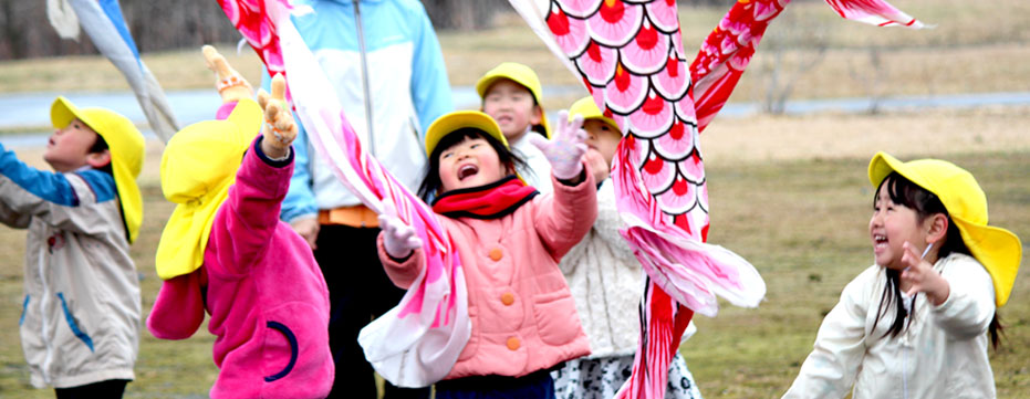 子どもたちが元気よくこいのぼりで遊んでいる写真