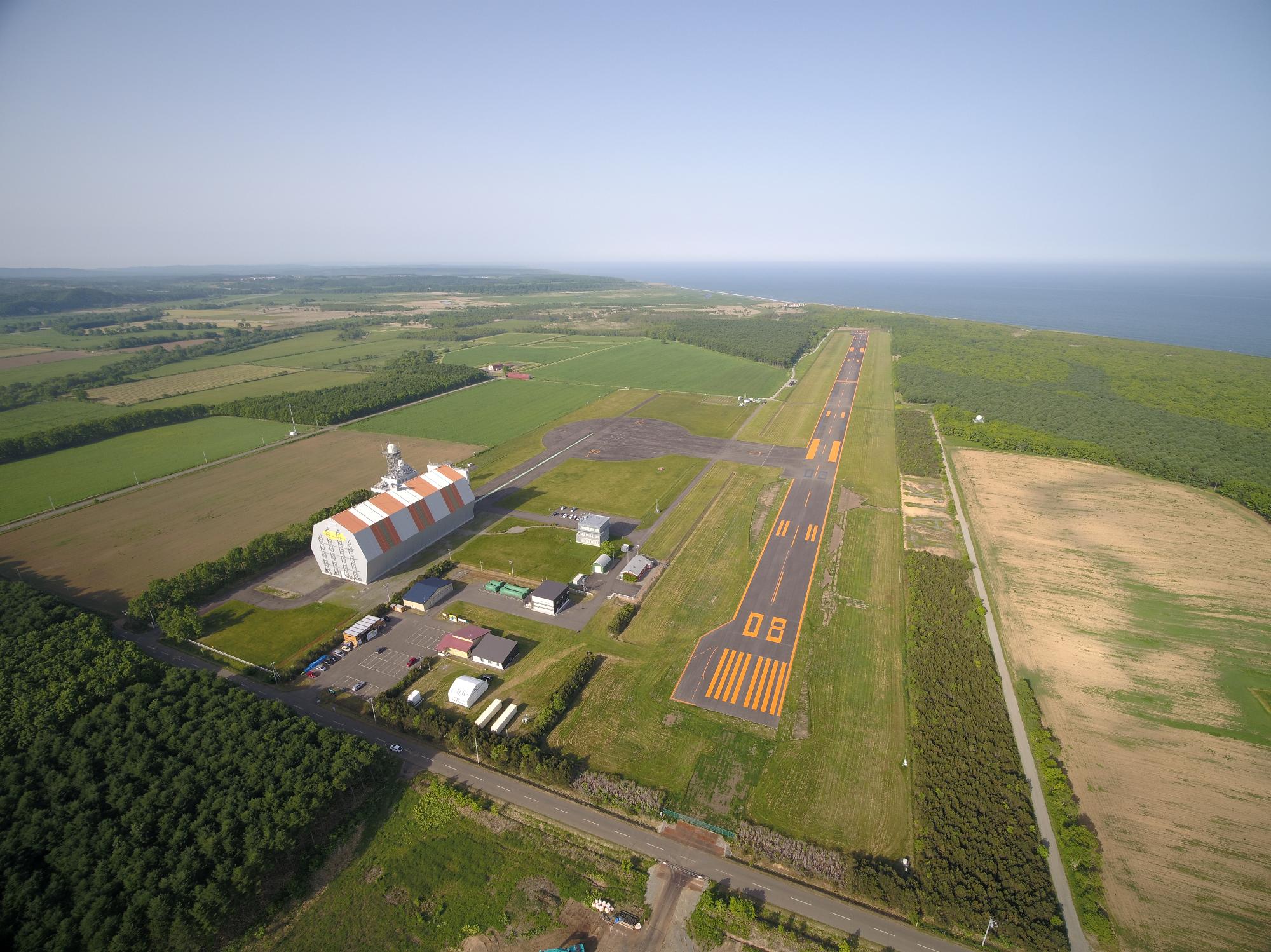 西側上空より鳥瞰で撮影された、大樹町多目的航空公園の全景写真。写真右側に滑走路が確認できる