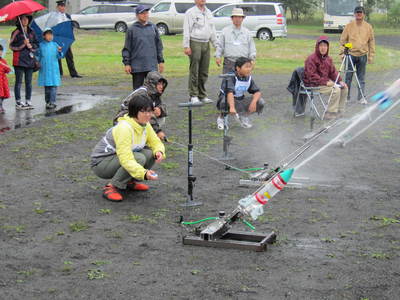 日本水ロケットコンテスト2011北海道ブロック大会にて、勢いよく水を噴き出して発射された水ロケットと、その隣で発射を待つ水ロケットの様子の写真