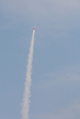 白い煙の尾をひいて飛行しているロケットの写真