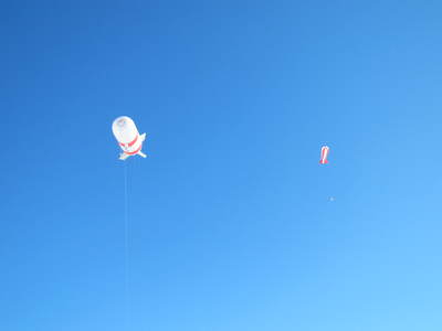青空に浮かんでいる小型飛行船型気球の写真