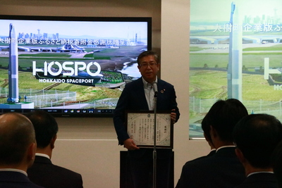 SORA集会室の式典会場にて、贈呈された感謝状を持ちつつスピーチを行う企業代表者の写真