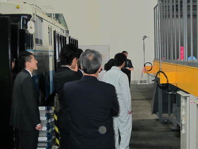 スライダー式放球装置を間近で見学する、「大樹町内施設バスめぐり」の参加者たちの写真