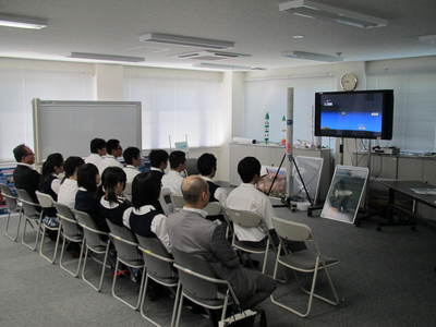 飛行管制棟内の一室にて着席して資料映像を鑑賞する、札幌日本大学高等学校の生徒たちの写真