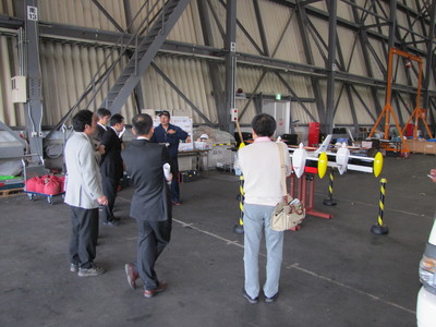 JAXA格納庫にてVTOL実験機を前に職員より解説を聞く、北海道高等学校理科研究会十勝支部訪問団の写真