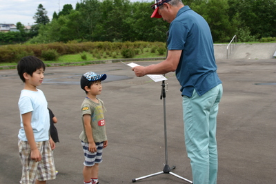 コンテストの表彰式で、小さな子供たちに賞状を読み上げている表彰している写真