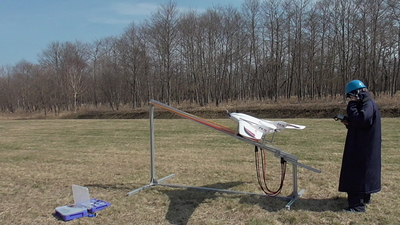 射出台に設置された固定翼型UAV（写真中央）と、そのそばに立つ観測スタッフ（写真右端）の写真