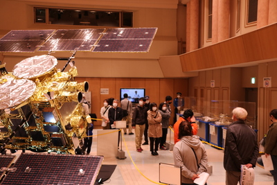 生涯学習センターのオークホールにおける、帰還カプセル特別展示会の開催風景写真。写真左側に「はやぶさ2」の実物大模型が確認できる