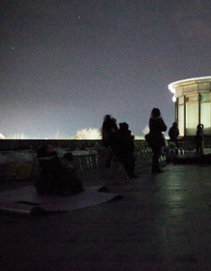 夜間の生涯学習センター屋上にて流星群の観測を試みる参加者たちの写真