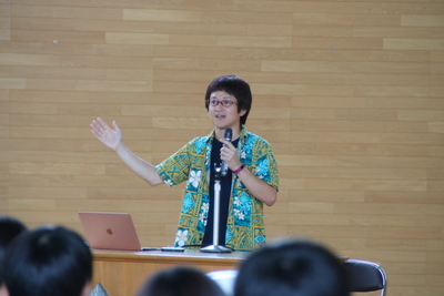マイクを片手に講演を行う稲飯助教授の写真