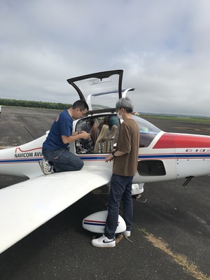 駐機したモーターグライダーのコクピット付近で作業を行うスタッフ2名の写真